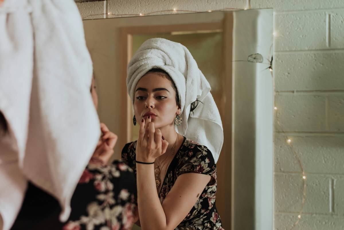 Woman using a ring light for makeup application with beauty light essential setup on vanity